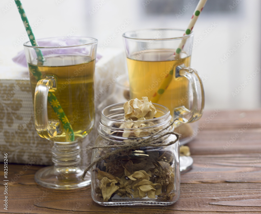 A festive still life with a decorative glass jar of dry flowers and two cups of fresh green tea with christmas patterned straws, light background A festive still life with a decorative glass jar of dry flowers and two cups of fresh green tea with christmas patterned straws, light background
