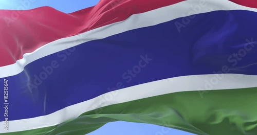 Gambian flag waving at wind in slow in blue sky, loop photo