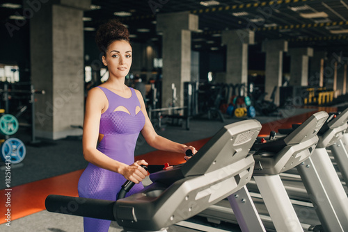 Smiling athletic woman resting on a treadmill