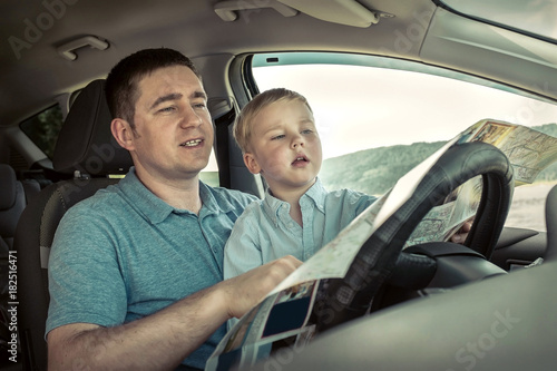 Father and son looking on map in car