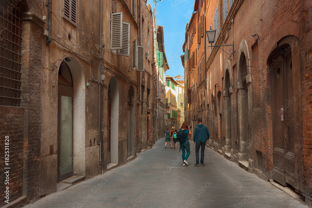 Beautiful medieval narrow street in the spring, Siena, Italy. Historic centre of Siena has been declared by UNESCO a World Heritage Site. Beautiful medieval narrow street in the spring, Siena, Italy. Historic centre of Siena has been declared by UNESCO a World Heritage Site.