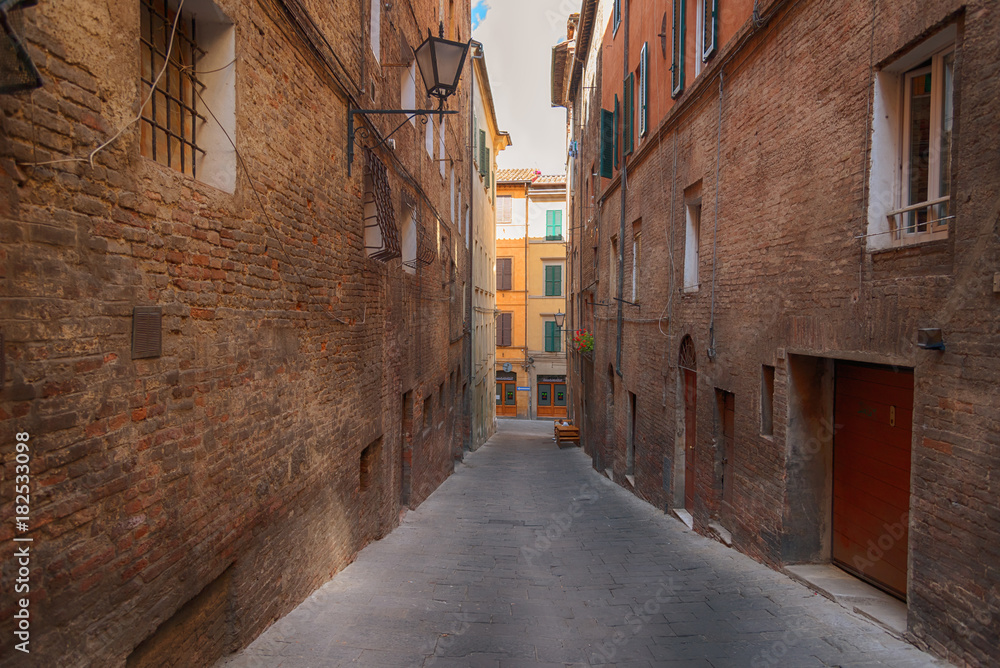 Beautiful medieval narrow street in the spring, Siena, Italy. Historic centre of Siena has been declared by UNESCO a World Heritage Site.