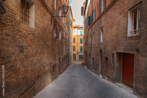Fototapeta Naklejka Na Ścianę i Meble -  Beautiful medieval narrow street in the spring, Siena, Italy. Historic centre of Siena has been declared by UNESCO a World Heritage Site.