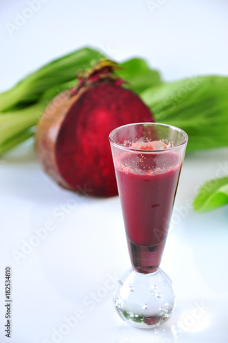 Beetroot Juice in Shot Glass with Fresh Beetroot on Background