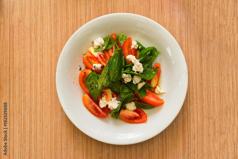 Salad with leaves, tomato and cheese. Overhead view. Selective focus. Salad with leaves, tomato and cheese. Overhead view. Selective focus.