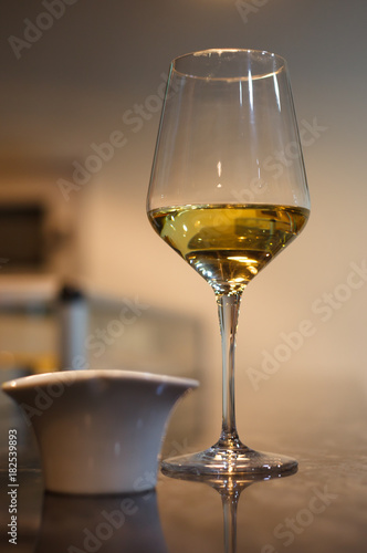 Glass of white wine on bar with small bowl of tapas