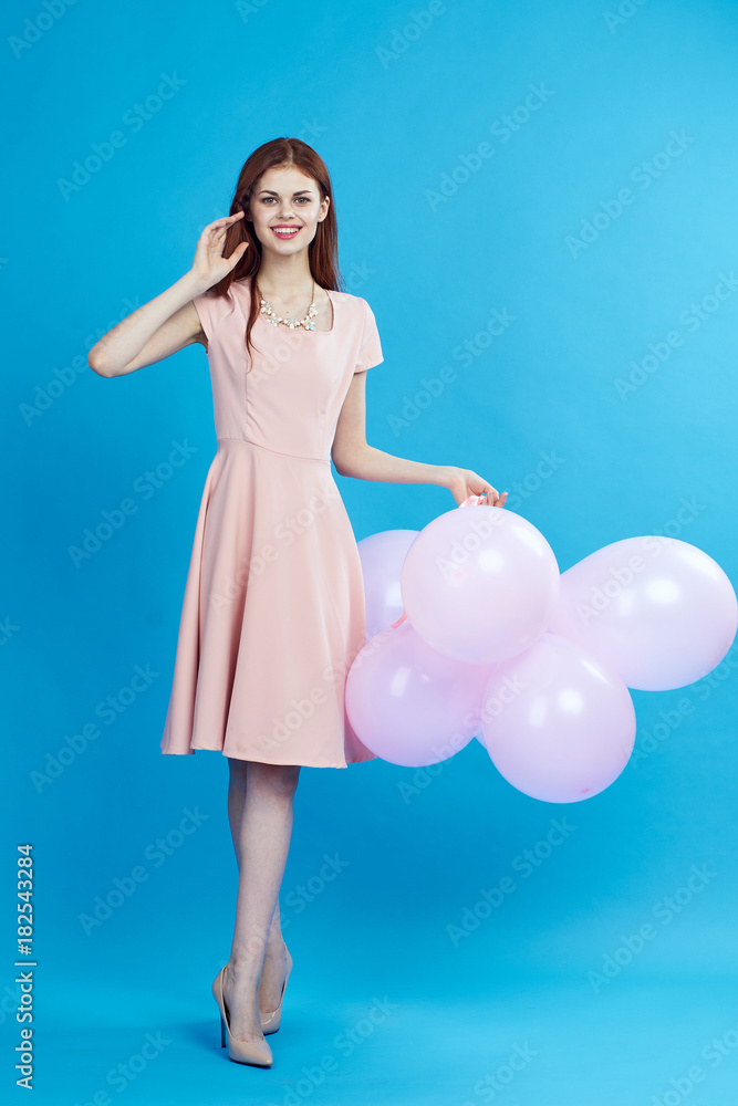 woman in shoes and in dress holds balloons