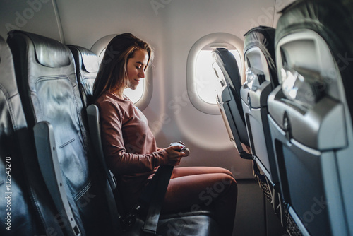 Girl is strapped on the plane near window