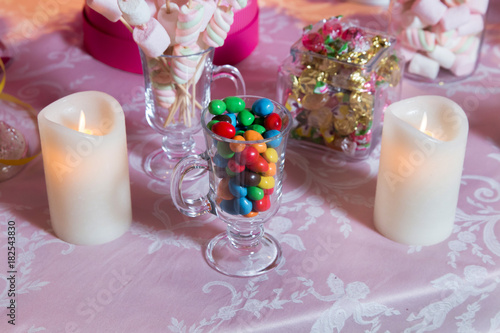 Colorful candy . Multi colored sweets . Colored candy in a glass . Round chocolate is very colorful . Candle .