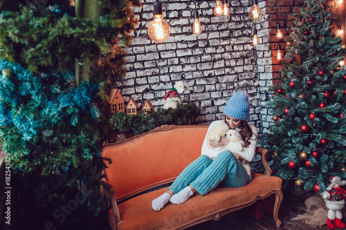 Beautiful woman with cute puppies sitting near Christmas tree. New Year. © kanashkin