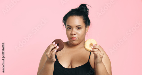 Plus size model in studio shoot happy smiling and eats a donut photo