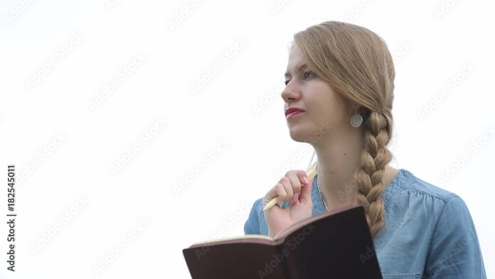 A young beautiful woman writes in her diary. She a novice writer. She composes, thinks and laughs. White background. A young beautiful woman writes in her diary. She a novice writer. She composes, thinks and laughs. White background.
