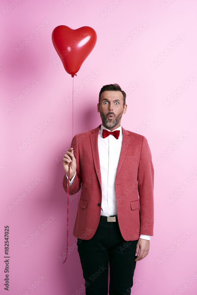 Surprised man holding heart shape balloon
