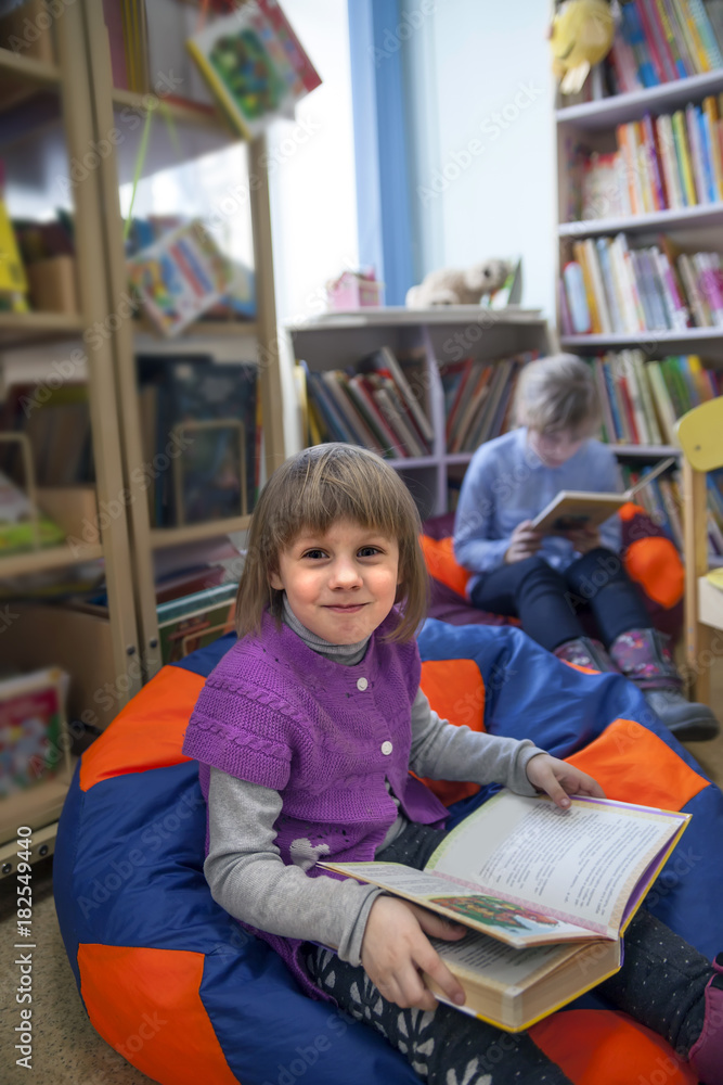 Child reading book in library. Child reading book in library.