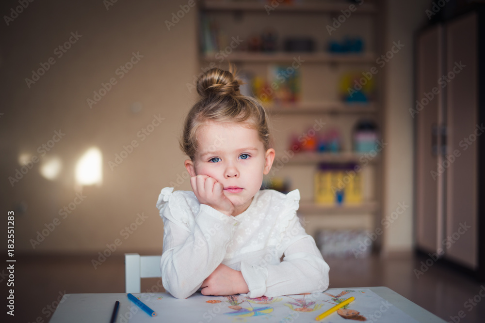 sad little girl sitting at table with painting sad little girl sitting at table with painting