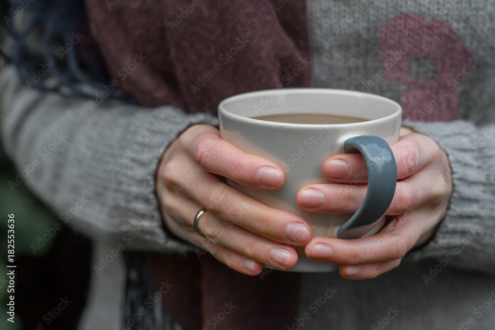 Hands holding a cup of warm coffee in a forest Hands holding a cup of warm coffee in a forest
