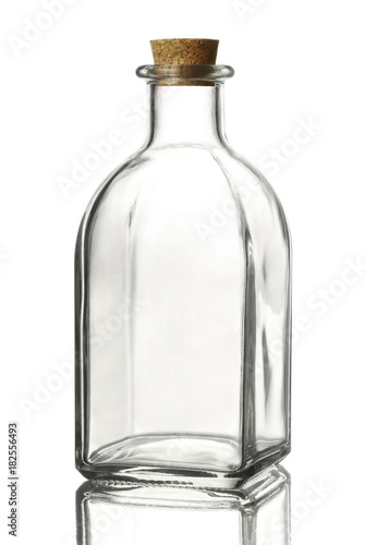 Empty transparent glass bottle of a square shape with a cork stopper on a reflective surface, isolated on a white background. photo