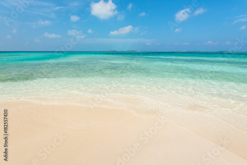 Empty tropical beach background. Horizon with resort island, sky and white sand in Maldives.