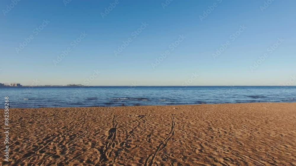 Moving slowly along the dark brown sandy beach towards the dark blue sea water. POV perspective. Moving slowly along the dark brown sandy beach towards the dark blue sea water. POV perspective.