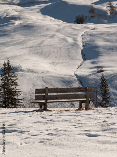 Wooden Bench Among Fresh Snow in Winter Sunny Day in Italian Dolomites Mountains