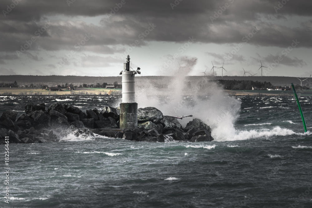 Waves splashing against rocks and a small lighthouse