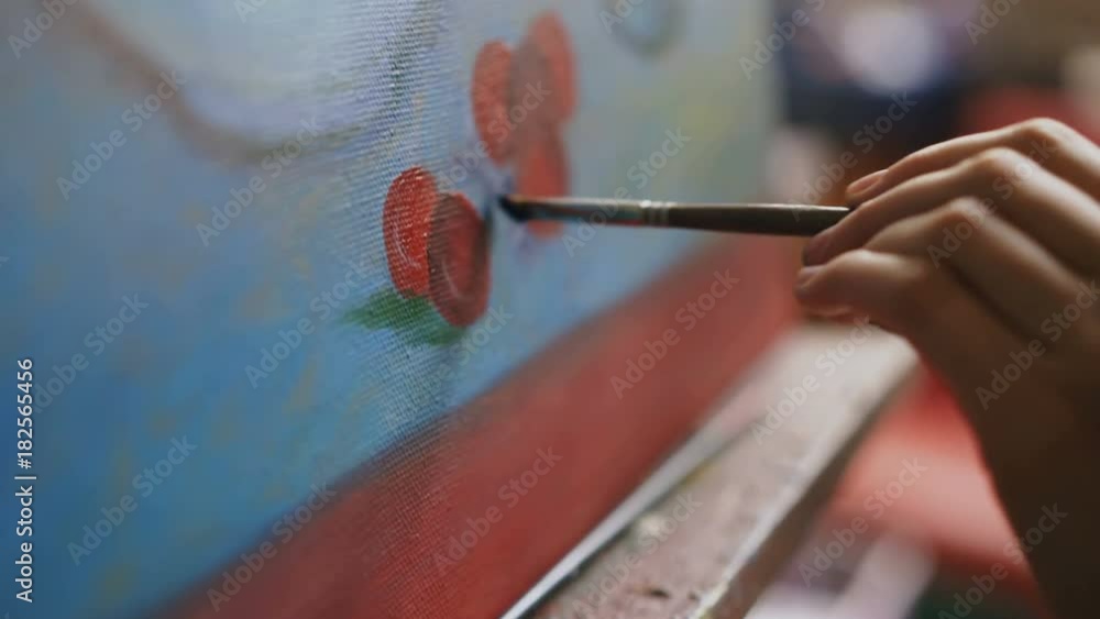 Close-up of artist woman's hand with brush painting still life picture on canvas in art studio Close-up of artist woman's hand with brush painting still life picture on canvas in art studio