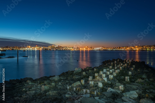 Night photo view of Portland Maine, USA. The smooth water, the city's buildings on the other shore are reflected in the water of the bay.
