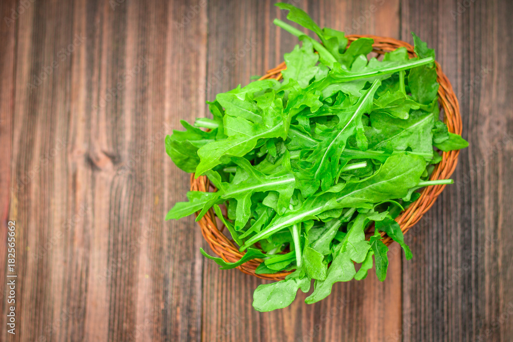 Fresh juicy leaves of arugula on a brown wooden table. Fresh juicy leaves of arugula on a brown wooden table.