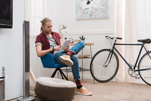 handsome man using tablet at home with bicycle