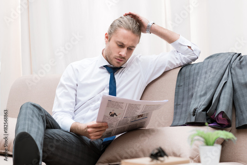 concentrated businessman reading newspaper on sofa at home © LIGHTFIELD STUDIOS