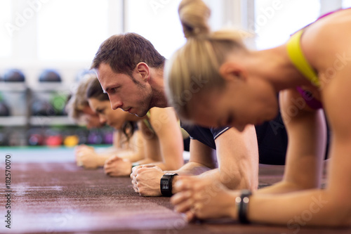 Fototapeta Naklejka Na Ścianę i Meble -  man at group training doing plank exercise in gym