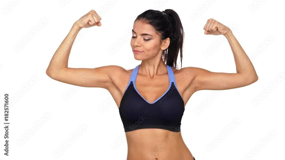Smiling brunette fitness woman showing her biceps and looking at the camera over white background Smiling brunette fitness woman showing her biceps and looking at the camera over white background