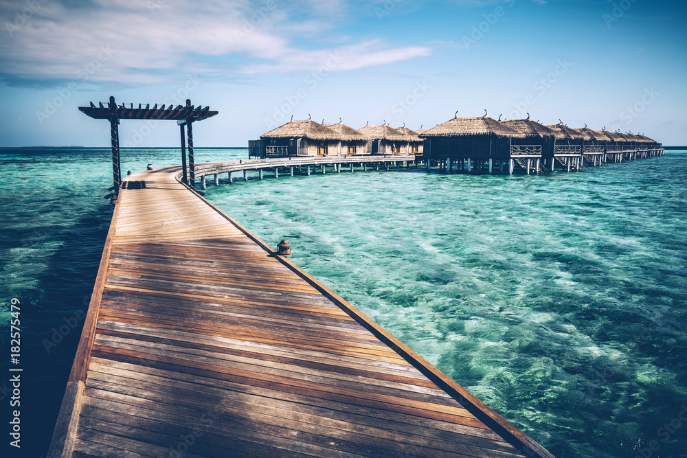Wooden jetty with arch on a clean turquoise ocean water.
