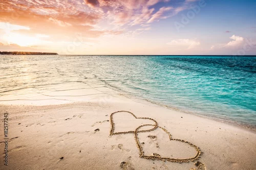 Obraz Dwa serca narysowane na piaszczystej plaży nad morzem.
