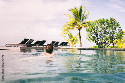 Woman swimming in a hotel pool in a tropical resort.