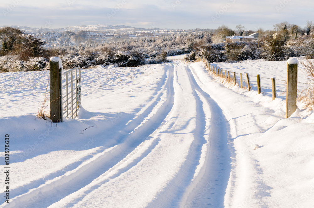 Snow covered rural lane with tyre tracks