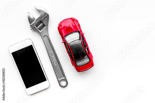 Choose car service. Wrench near car toys and cell phone on white background top view copyspace