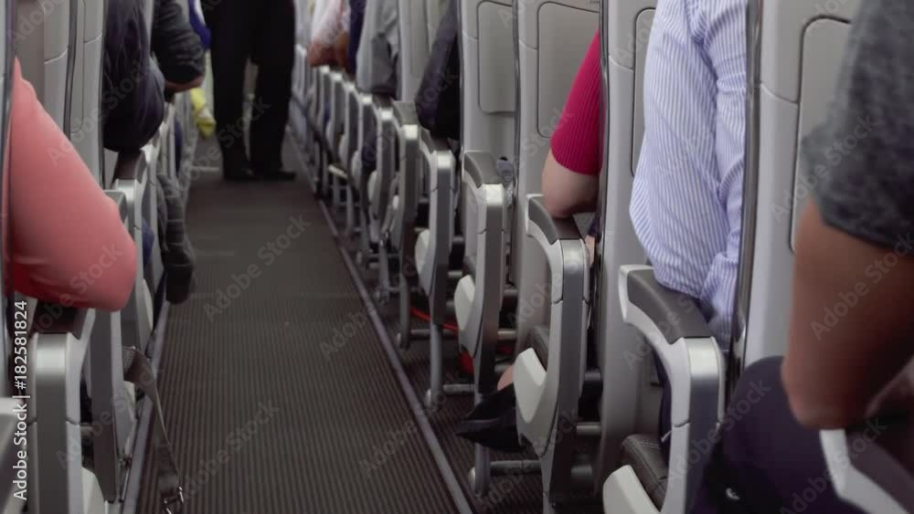 Inside view of airplane aisle during flight. Passengers sitting in their seats, cabin crew starts passenger service Inside view of airplane aisle during flight. Passengers sitting in their seats, cabin crew starts passenger service