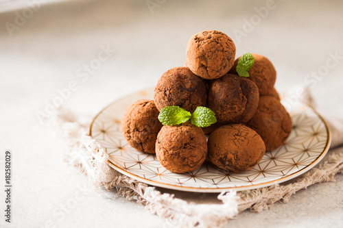 Сhocolate truffles with cocoa powder on white dessert plate