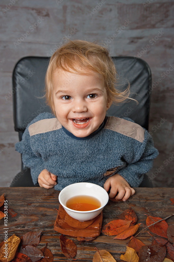 A little boy drinks tea from a white bowl.
A little boy drinks tea from a white bowl.