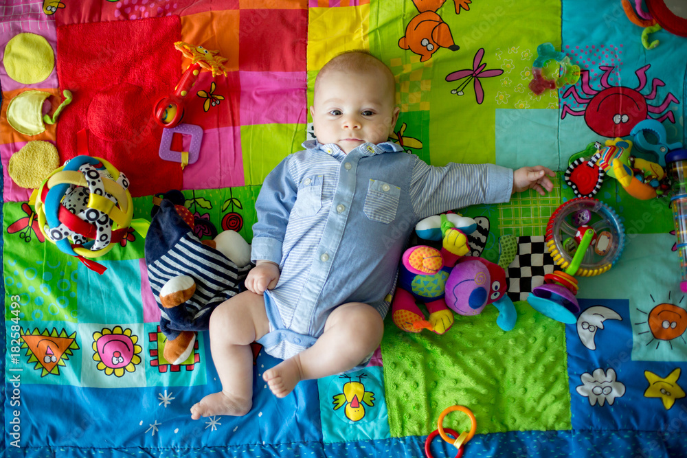 Obraz premium Happy three months old baby boy, playing at home on a colorful activity blanket