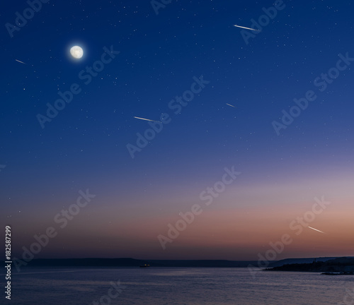 Moon and stars over the calm sea.