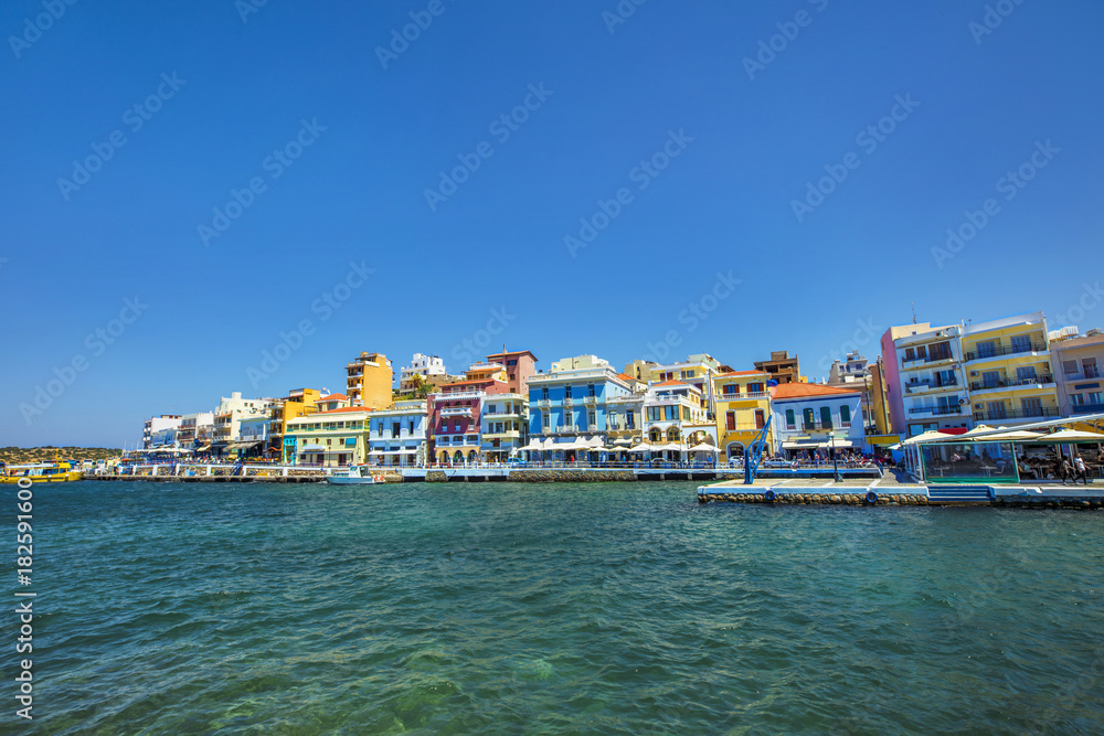A calm marine landscape with buildings under a clear blue sky