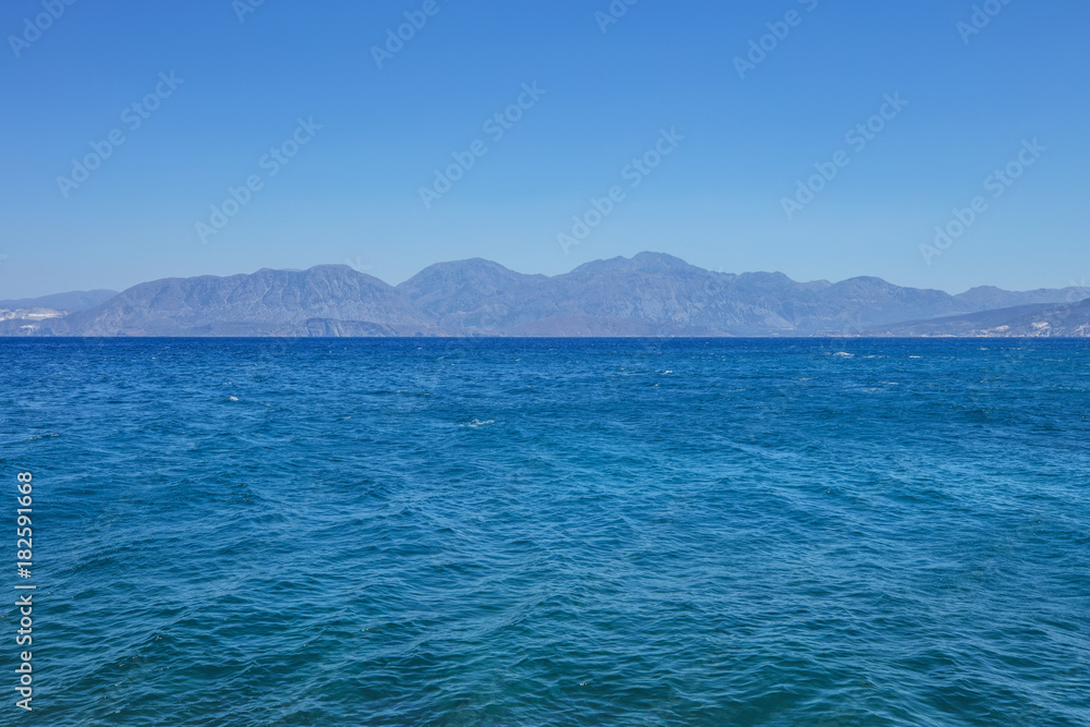 A calm marine landscape with mountains under a clear blue sky A calm marine landscape with mountains under a clear blue sky