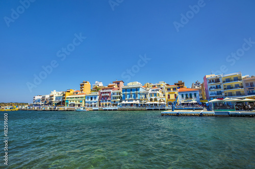 A calm marine landscape with buildings under a clear blue sky