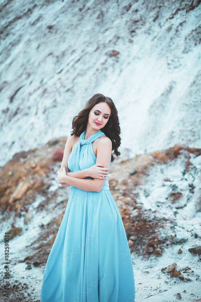 Portrait of the attractive caucasian woman with long dark hair, pretty girl in the blue dress and with diadem in the hair against the beautiful background of the landscape, lake and mountains