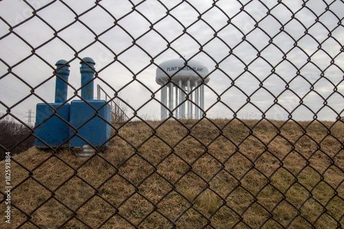 Flint Michigan Water Crisis. The Flint Michigan water tower seen through a chain link fence. Flint made national headlines when the city water supply was contaminated with lead.