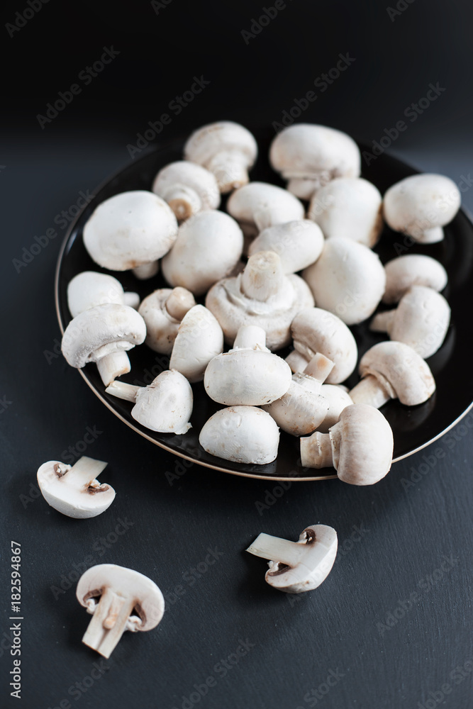 Mushroom champignon on black background, sliced and whole. Autumn raw Mushrooms. Mushroom champignon on black background, sliced and whole. Autumn raw Mushrooms.