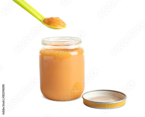 Spoon and jar with healthy baby food on white background