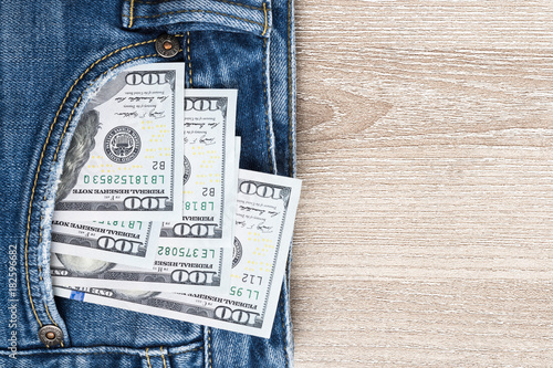 Money in pocket of blue jean on wooden background with copy space.